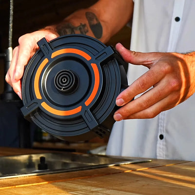 Person holding Stoke Voltaics kettle pot with unique orange heating element above a sink