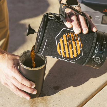 Pouring coffee from Stoke Voltaics all-purpose electric kettle French press into a mug outdoors